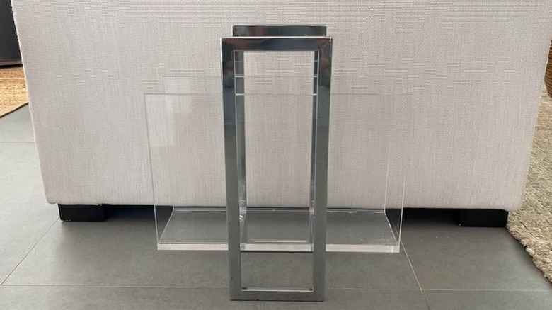 Lucite magazine rack with book or magazine on stone surface next to decorative vases