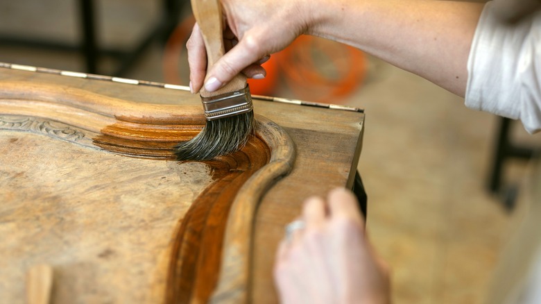 A person restores an antique wooden piece of furniture