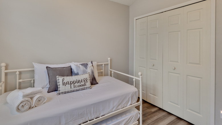 A trundle bed with white sheets sits in a children's room.