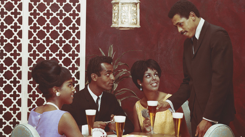 Two couples enjoying a 1960s dinner party with champaigne
