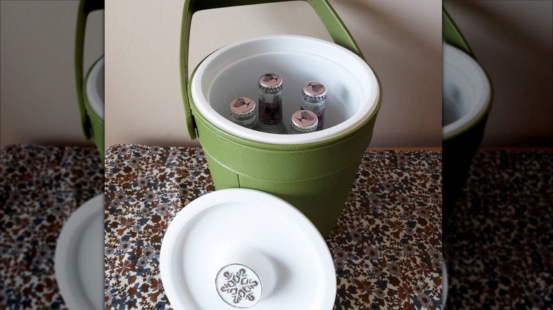 A green Rubbermaid ice bucket with the lid off, showing how four wine cooler bottles can fit inside.