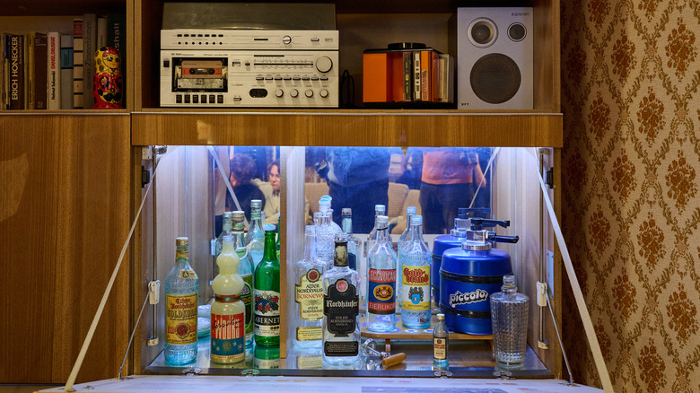A wooden bar cabinet with bottles of alcohol and a retro sound system.