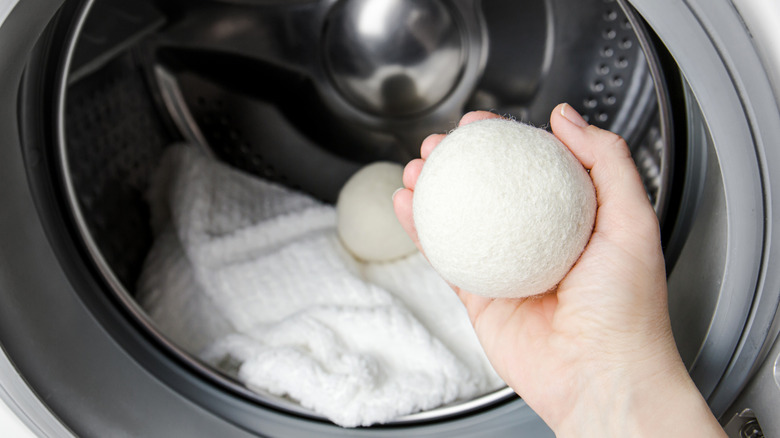 A person putting wool dryer balls in with their laundry