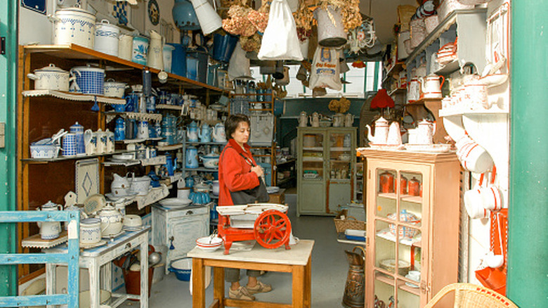 A person with a brown purse browsing through a vintage shop filled with kitchenware and gadgets