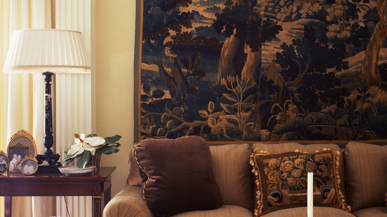 Living room with warm blue and orange landscape tapestry hung behind sofa