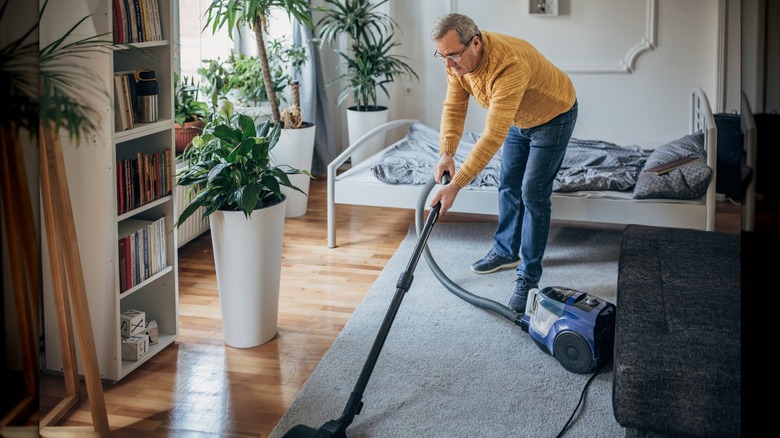 man vacuuming bedroom
