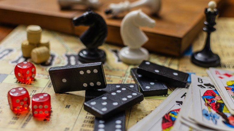 A close-up still life of various classic board game pieces including dice and chess pieces