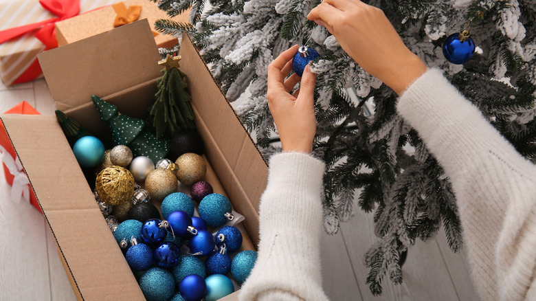 Woman putting Christmas toys in cardboard box at home