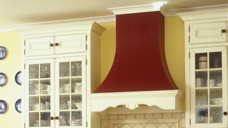 An ornate, red and cream hood situated between two glass cabinets.