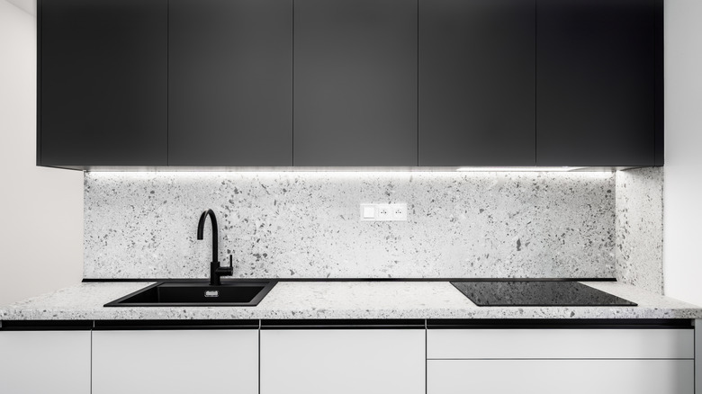 A small, modern galley kitchen with black upper cabinets and white lower cabinets.