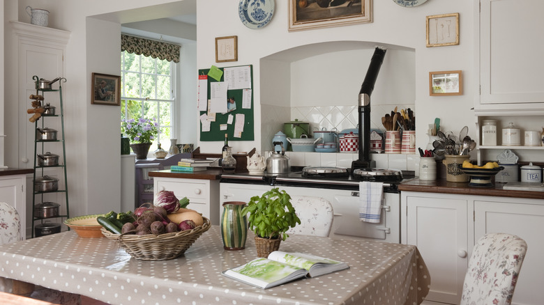 A kitchen table with cloth in a small kitchen by the stove.