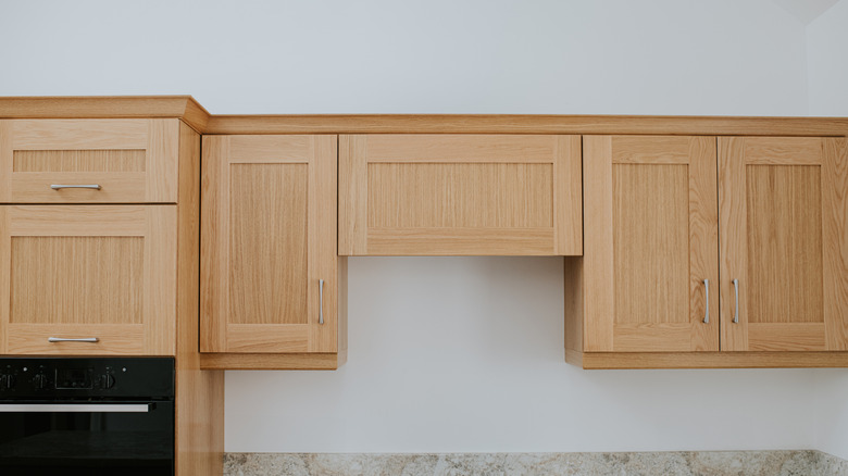 Floating wooden upper cabinets with Shaker-style doors on a white wall.