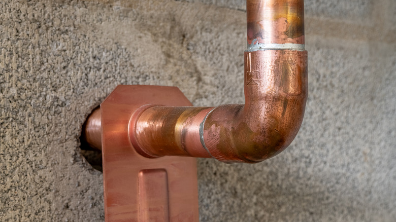 Copper plumbing line running through a concrete block wall