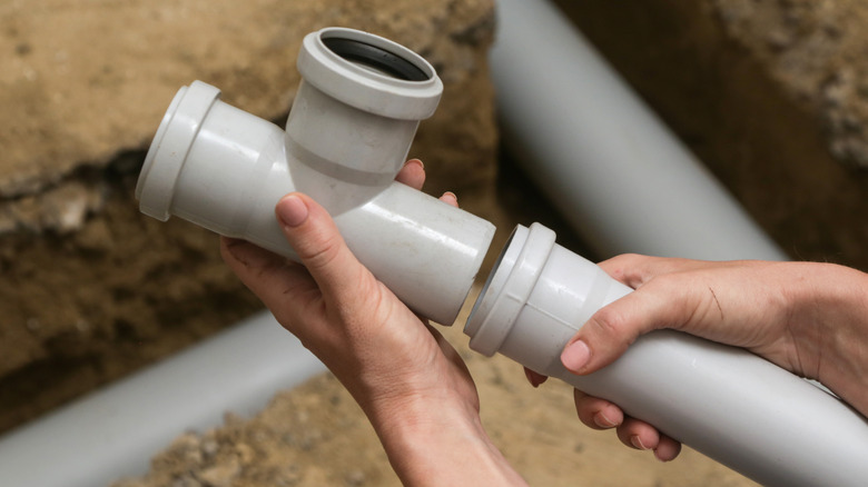 Person connecting PVC pipes during installation in a house