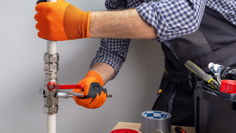 Plumber using a wrench to work on a plumbing line