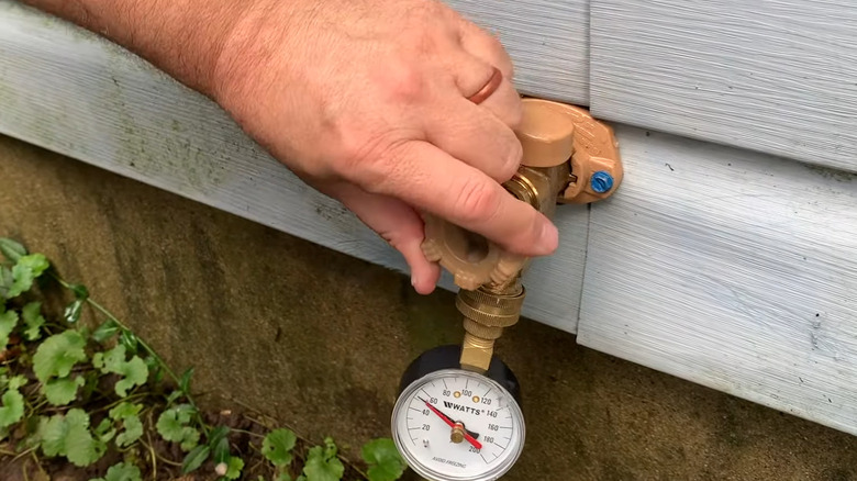 Person using a water pressure gauge on an outside spigot to test the home's water pressure