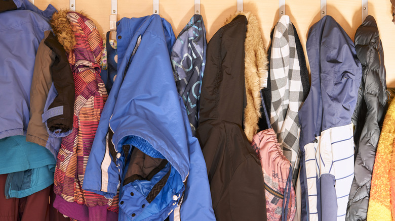 Lots of winter coats hanging on hooks