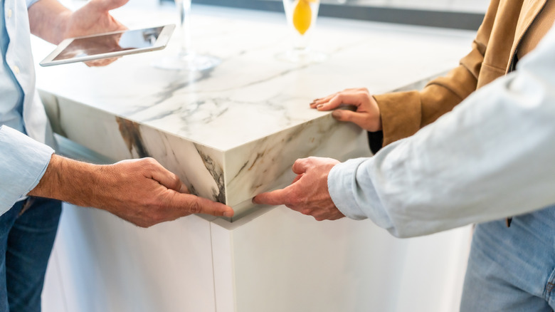 Homeowners running their fingers over the pencil edge of their kitchen countertop