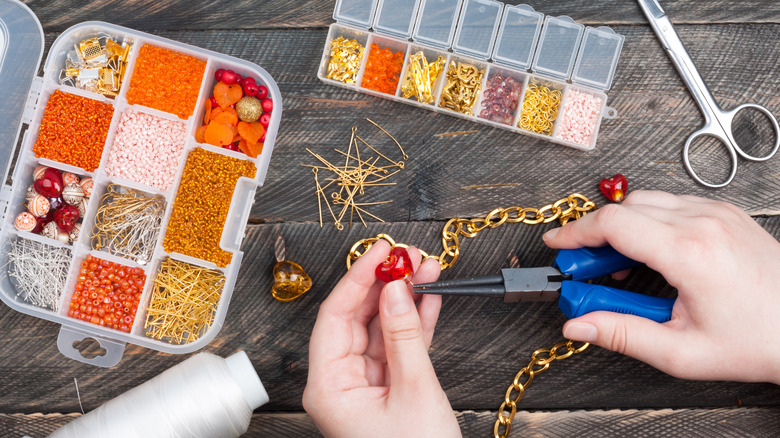 Hands crafting jewelry with beads and chain