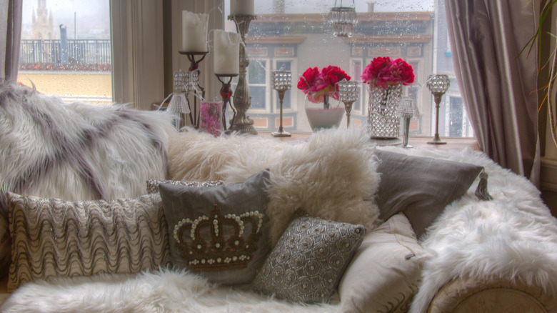A sofa with faux fur pillows and blankets.
