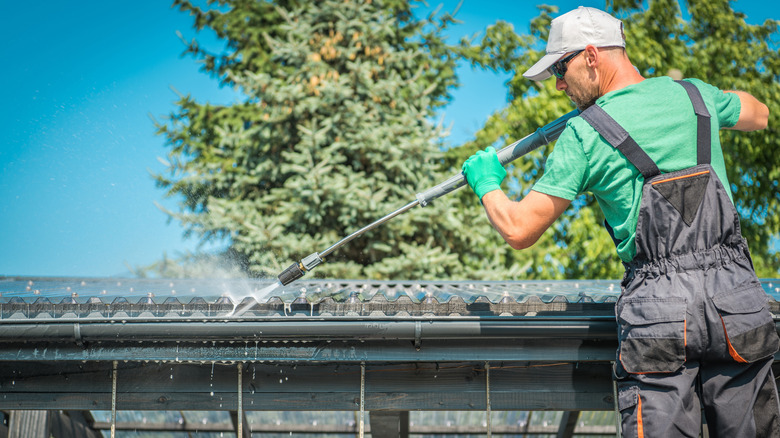Man pressure washing gutters