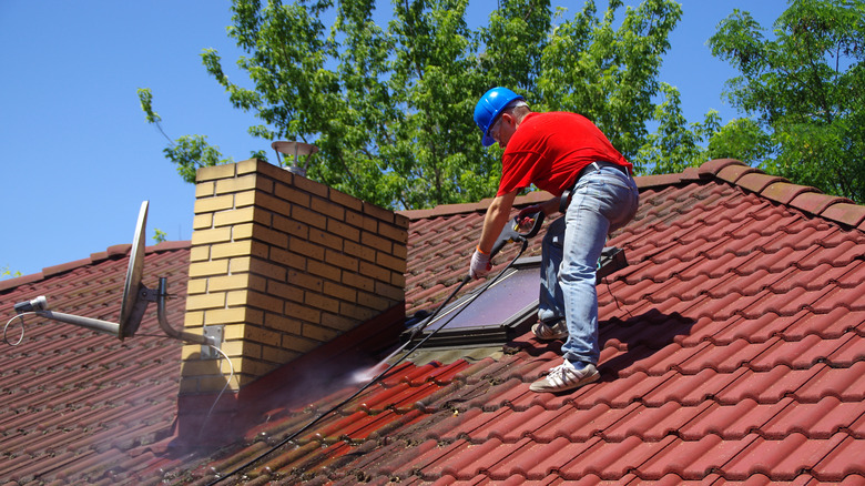 Man pressure washing roof