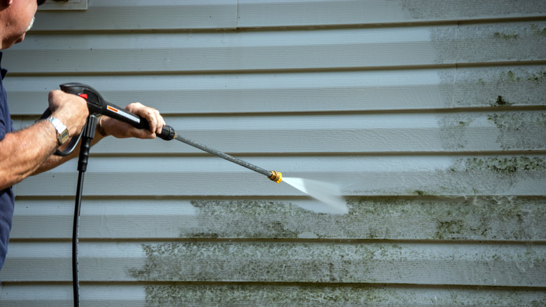 Man pressure washing siding
