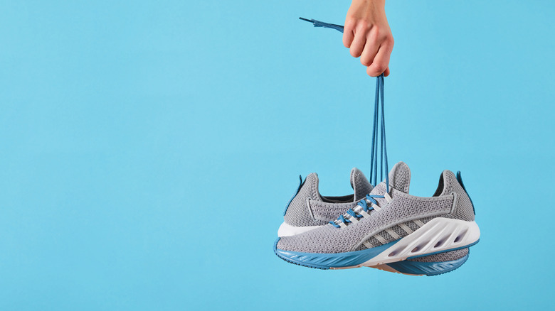 hand holding tennis shoes by laces