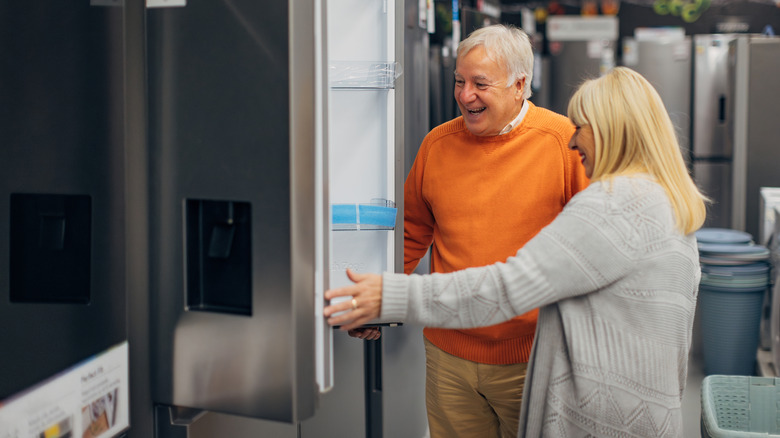 Elderly couple looking at French door refrigerator in store