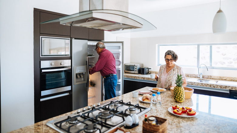 Elderly man getting food out of side-by-side fridge