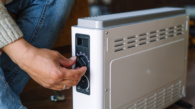Close up of person turning the dial on a space heater