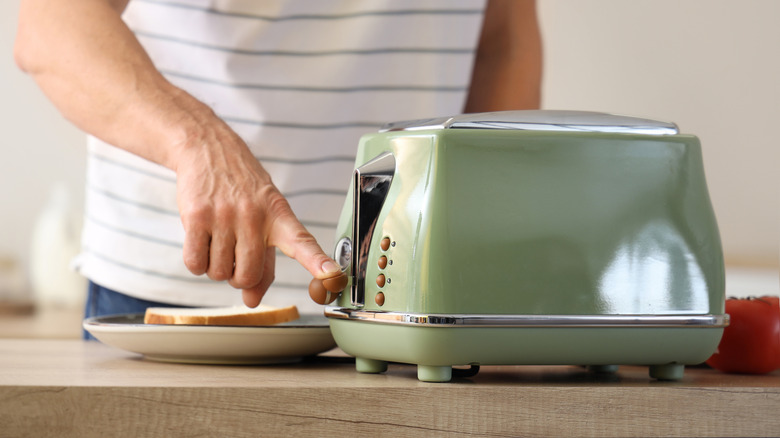 Close up of man using green toaster
