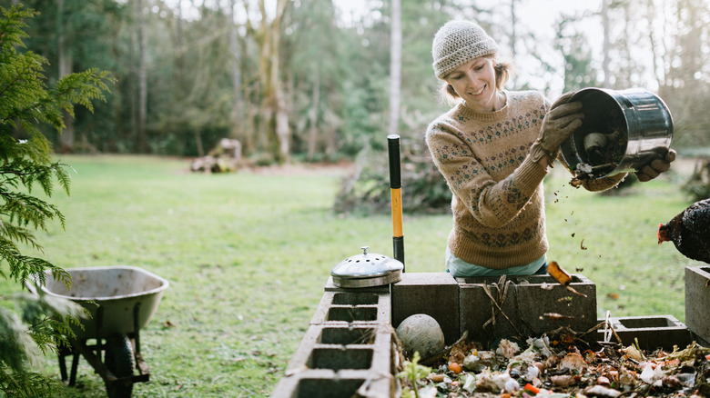woman adding scraps to compost pile