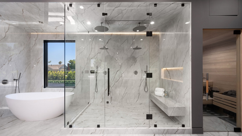 Modern luxury bathroom with large glass shower, freestanding tub, featuring marble walls and floors