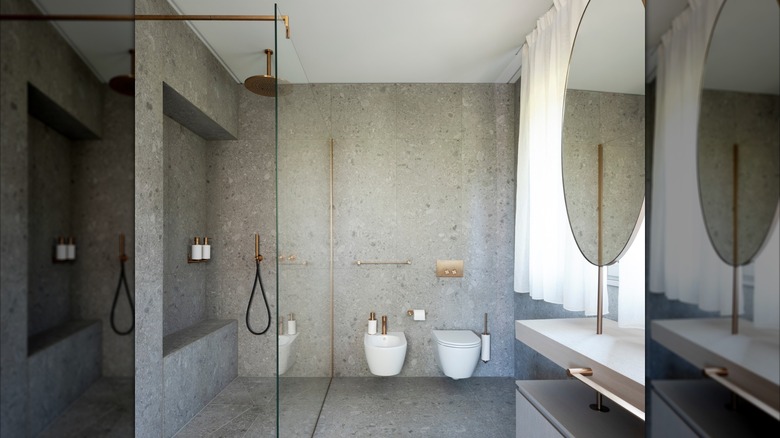 Modern bathroom with large granite slabs on walls and floor and open glass shower
