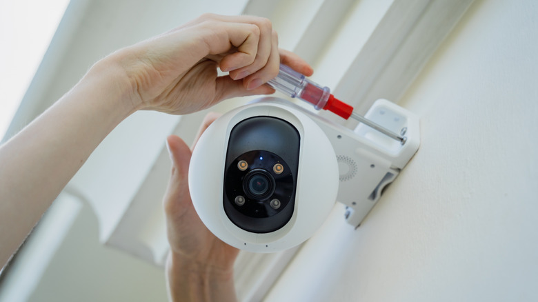 A technician installs a CCTV camera on the facade of a residential building