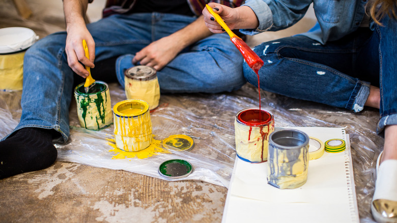 People holding paint-dipped brushes