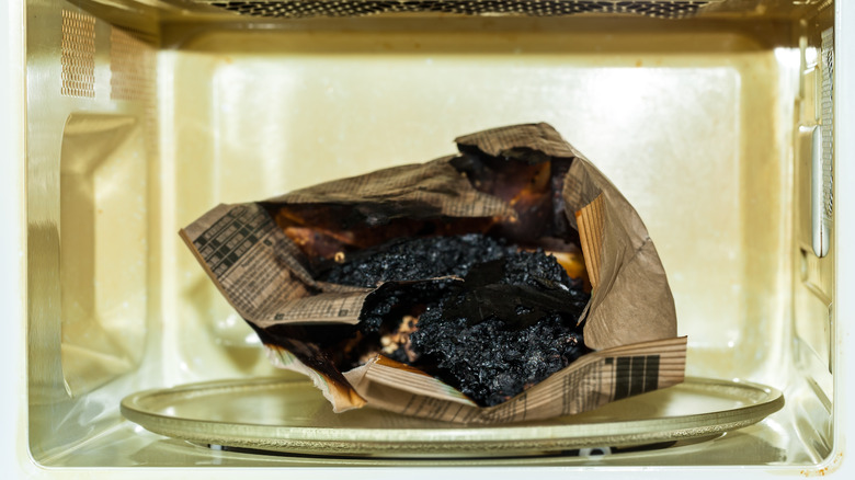 A charred microwave popcorn bag in a microwave