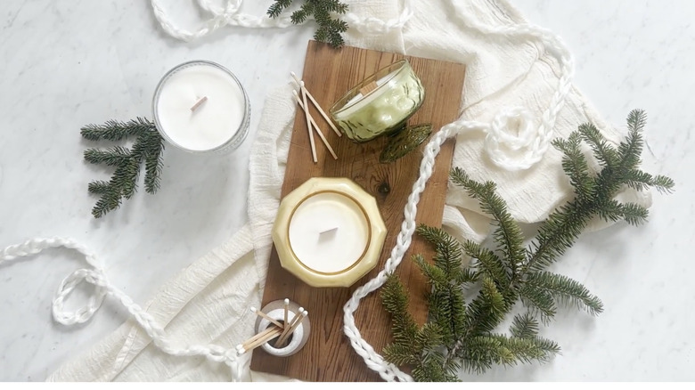 Candles made in vintage-inspired heat-safe jars sit on a decorated tabletop.