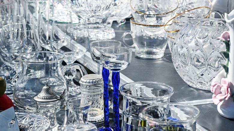 A thrift store shelf with various crystal and glass dishes.