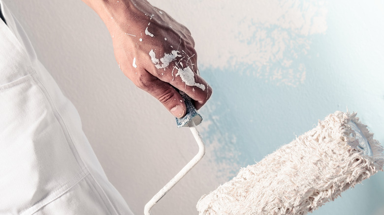 Decorator with paint on hand holding roller