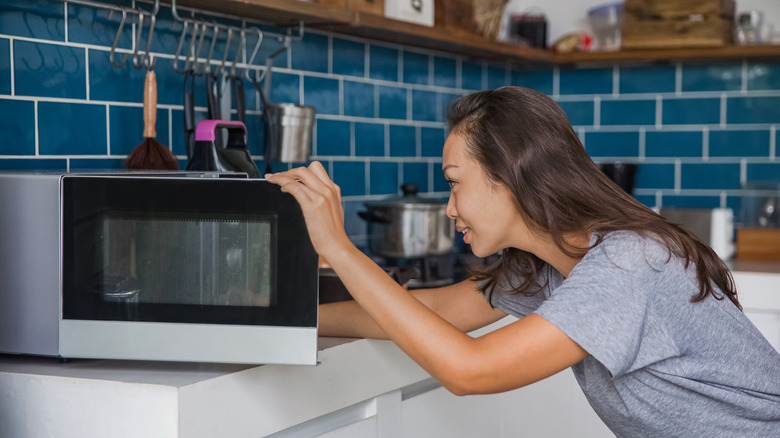 woman looking at microwave door