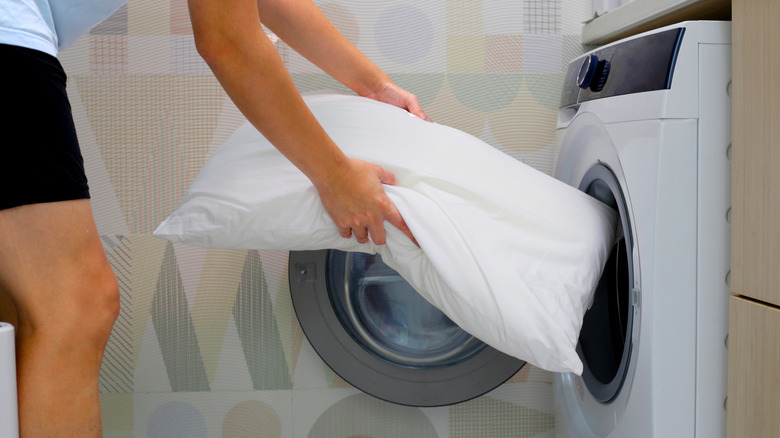 Person putting pillow in washing machine