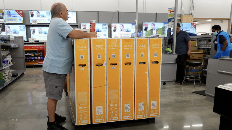 Man standing near a stack of boxed TVs at Walmart