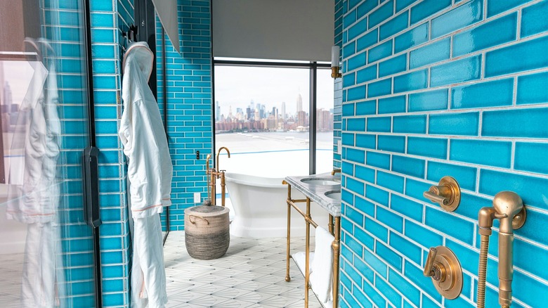 A blue-tile bathroom with a bathtub, a sink and a window