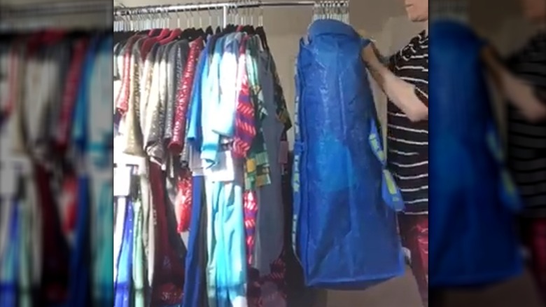 Woman slipping IKEA IKEA FRAKTA over hangers full of clothes