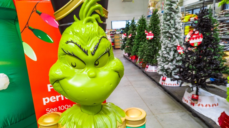 Grinch holiday decor nearby some Christmas trees.
