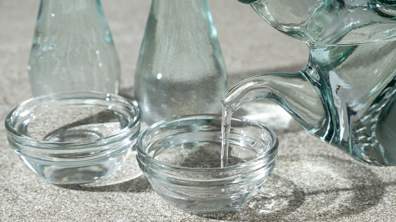 Someone pouring distilled white vinegar into a bowl