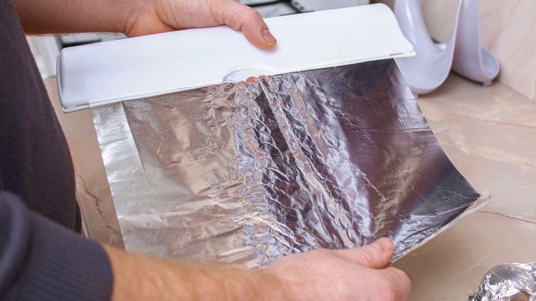 person tearing aluminum foil