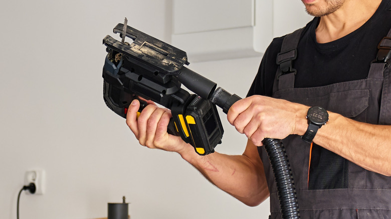 Man connecting hose to electric jigsaw